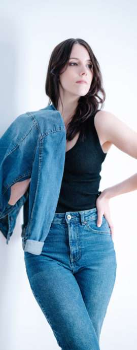 Portrait mode en lumière naturelle d’une jeune femme en jeans et débardeur noir, réalisé par un photographe professionnel à Montréal